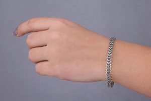 Närbild på en hand som bär ett silverfärgat länkarmband.